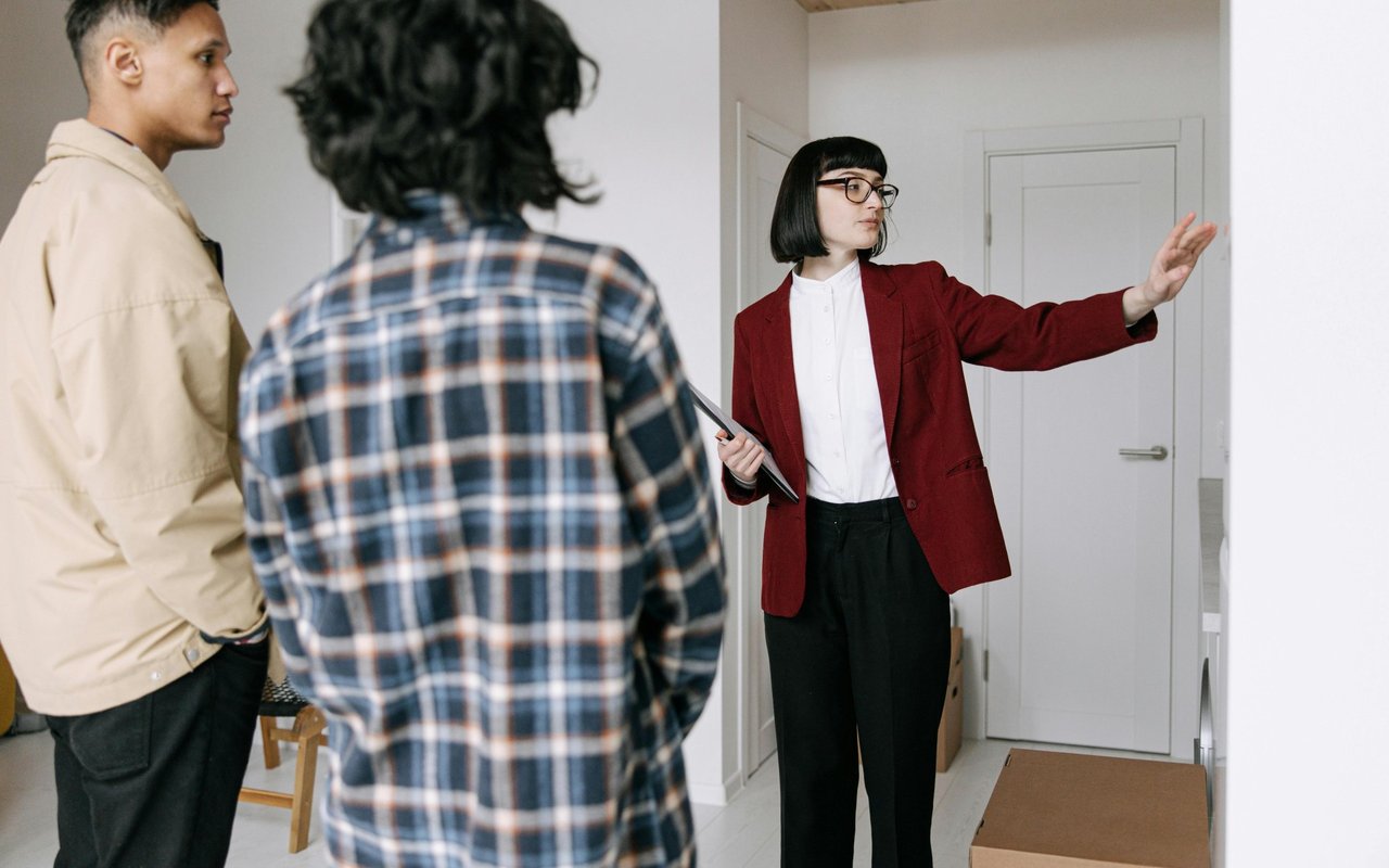 Real estate agent showing two clients a bright, unfurnished home