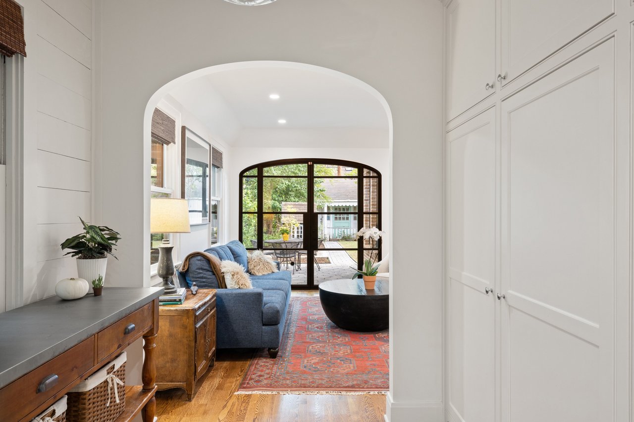 Living room with a blue sofa and arched black-framed doors opening to a patio.