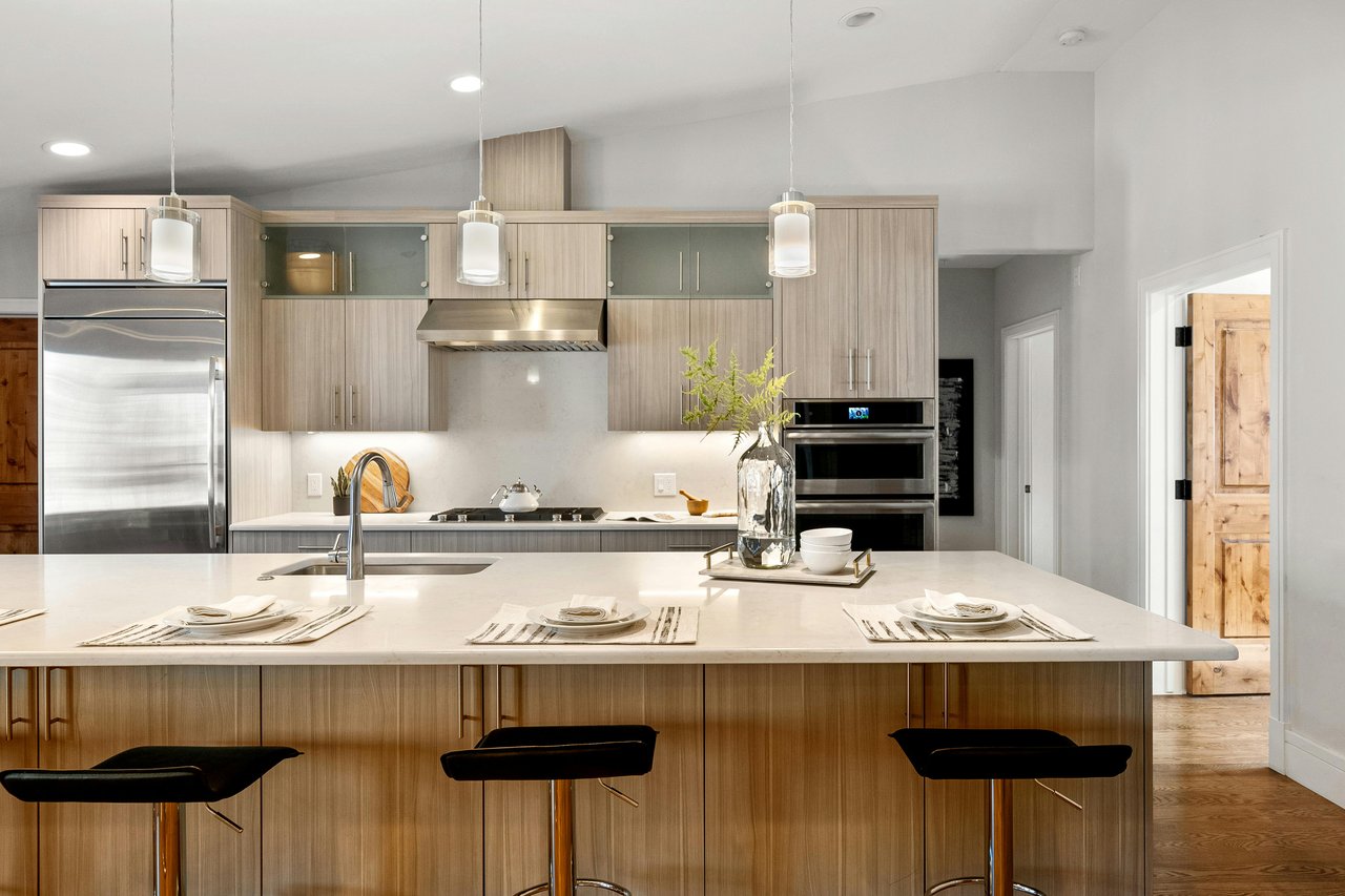 Contemporary kitchen with a large white island, light wood cabinetry, and stainless steel appliances.