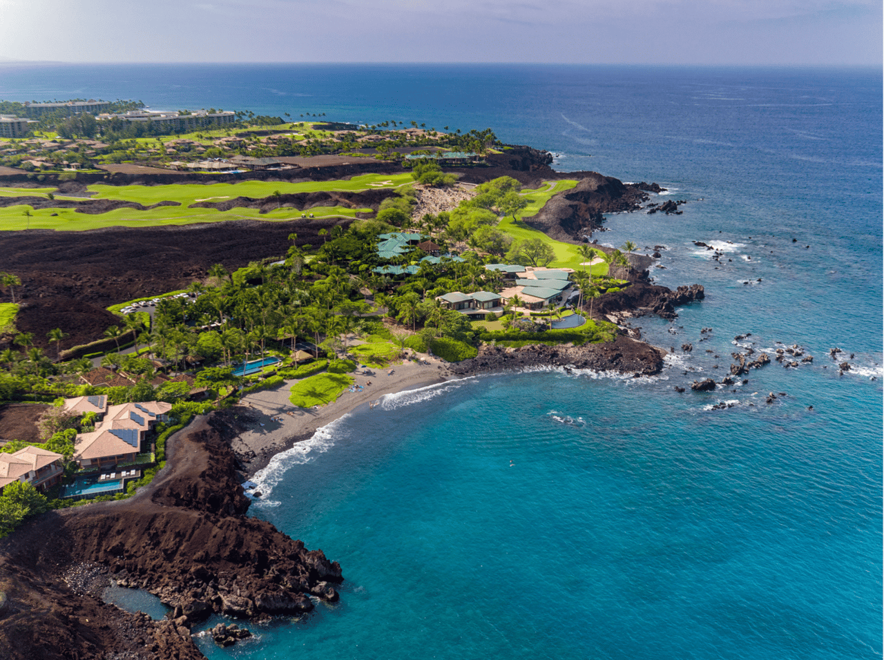 Aerial view of coastal homes and golf course beside turquoise ocean in Kamuela.