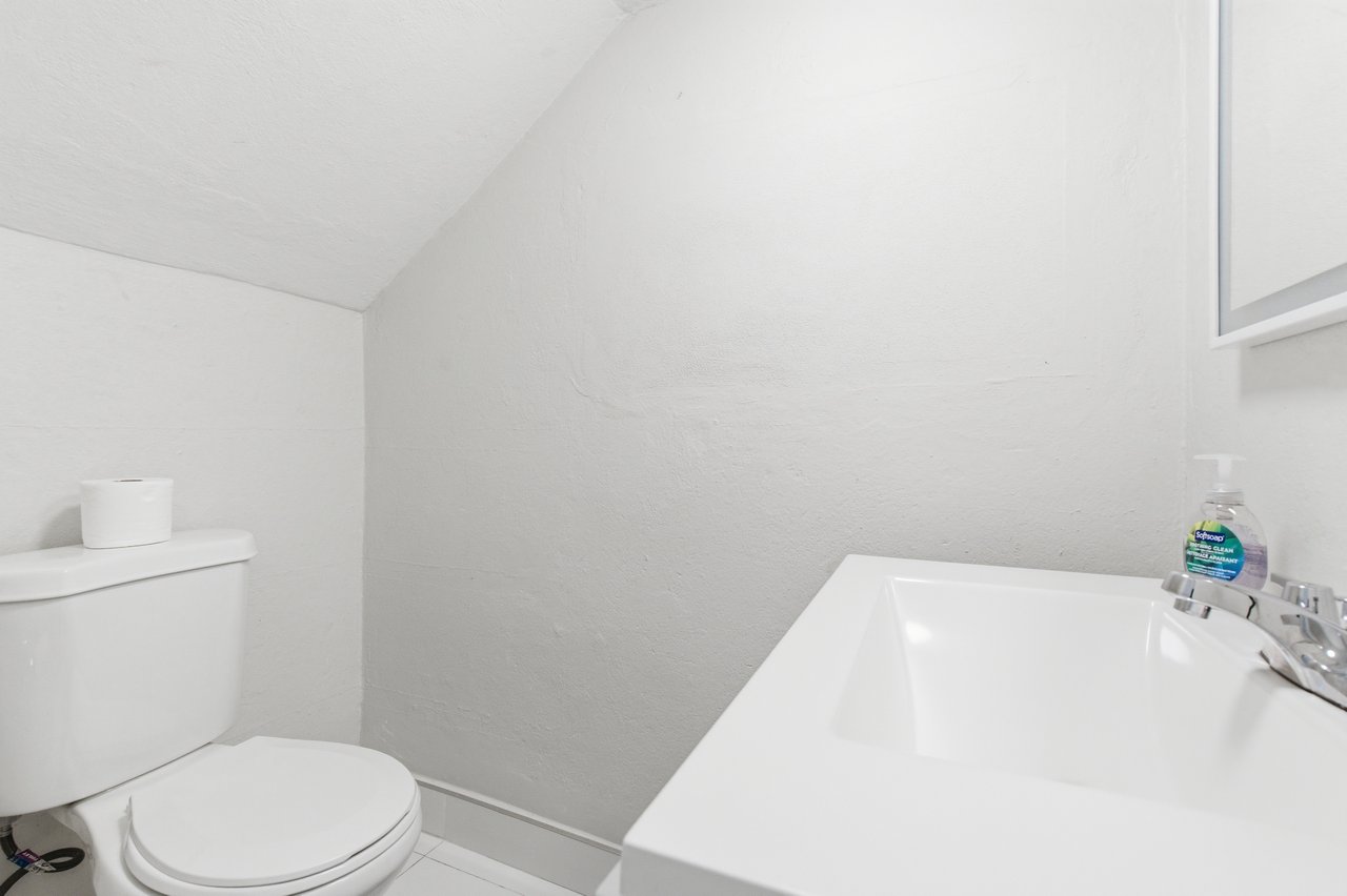 Compact white bathroom with a toilet beside a built-in bathtub and chrome faucet.