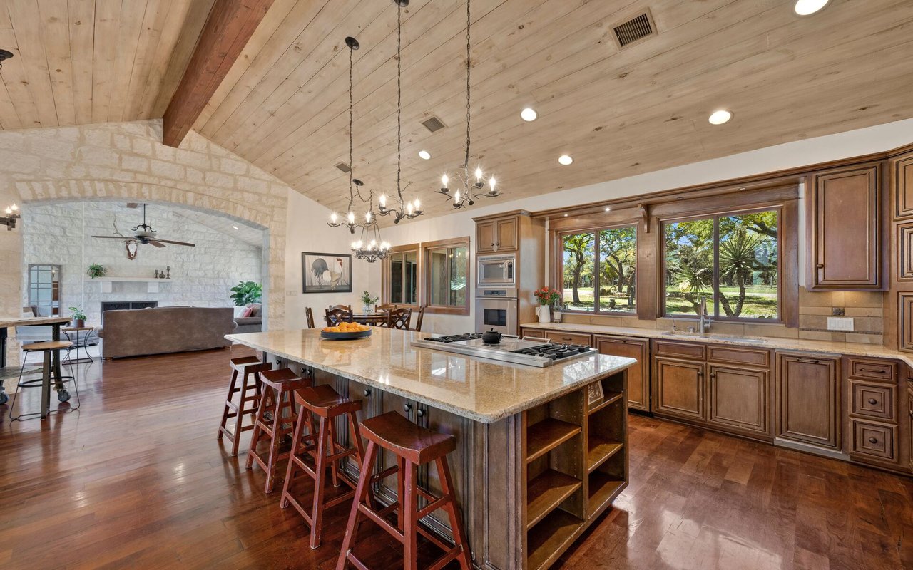 Kitchen with a granite island, wood cabinetry, and large windows overlooking trees