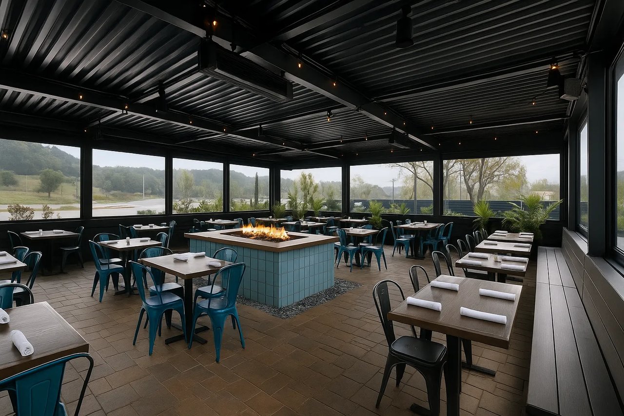 Covered restaurant patio in Aliso Viejo with a central fire pit, teal chairs, and neatly set tables, overlooking green hills.