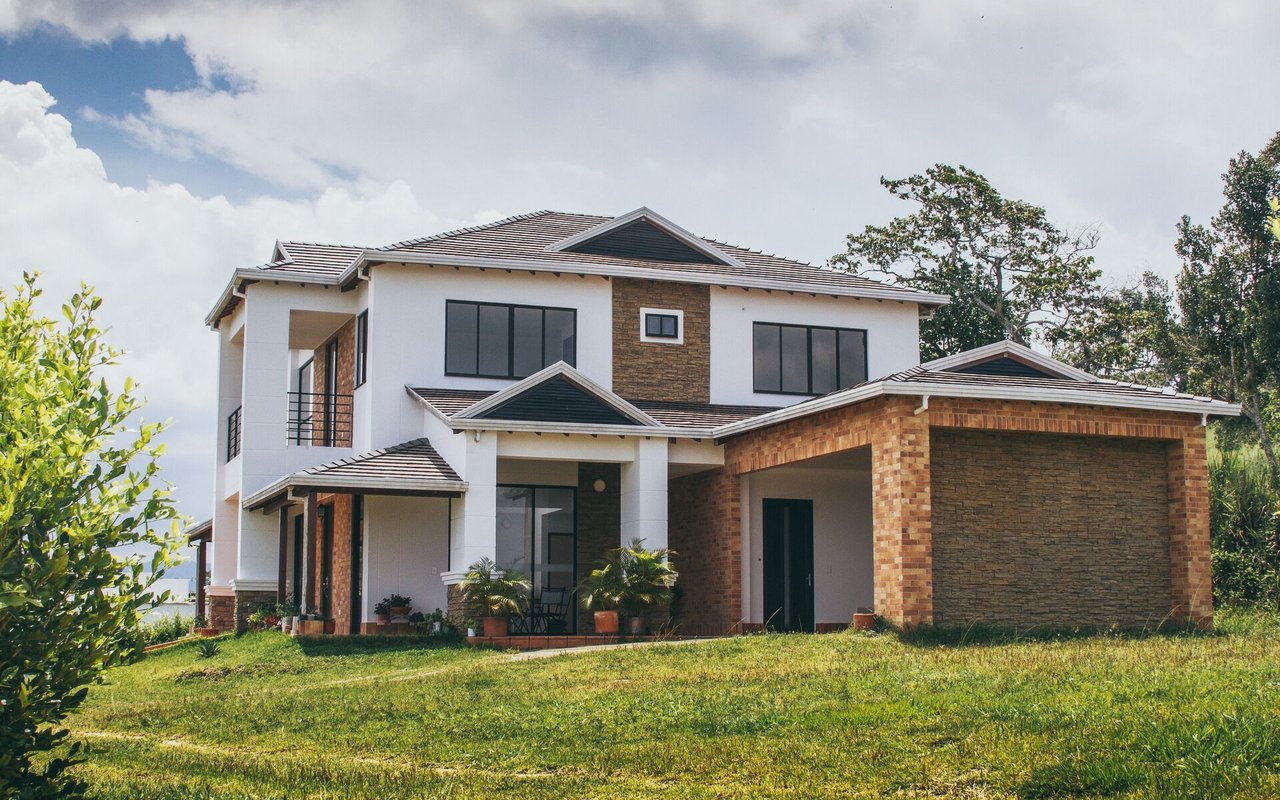 Modern two-story home with white siding, brick and stone accents, and a broad green lawn.