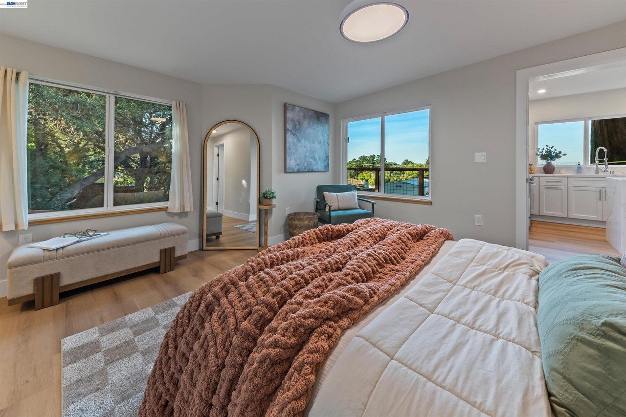 Bedroom with a rust-colored textured throw, large windows, and a cushioned bench.
