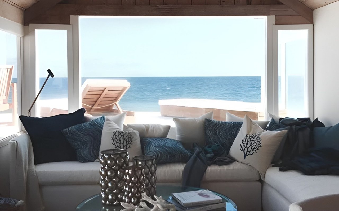 Coastal living room with a white sectional, navy cushions, and ocean views through wide windows.