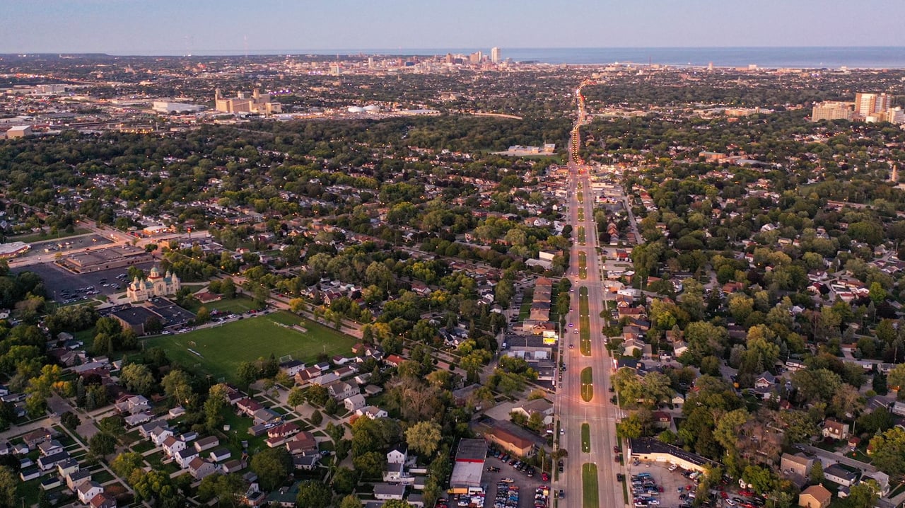 Aerial view of Greenfield, Wisconsin showing residential neighborhoods, major roads, and the Milwaukee skyline in the distance.