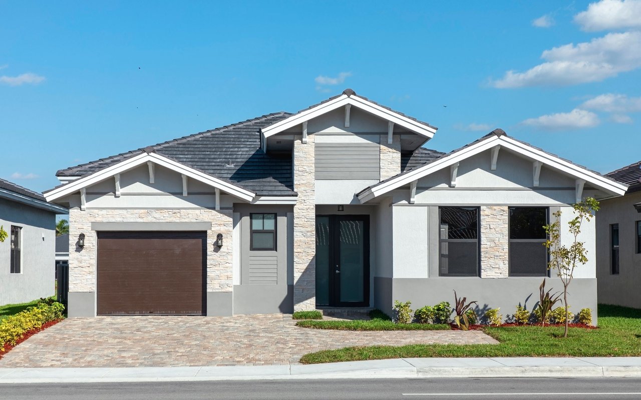 Modern single-story home with pale stone facade, dark tiled roof, and attached garage.
