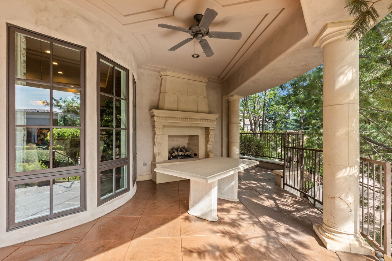 Covered guest-house patio with a stone fireplace, built-in counter, and ceiling fan.