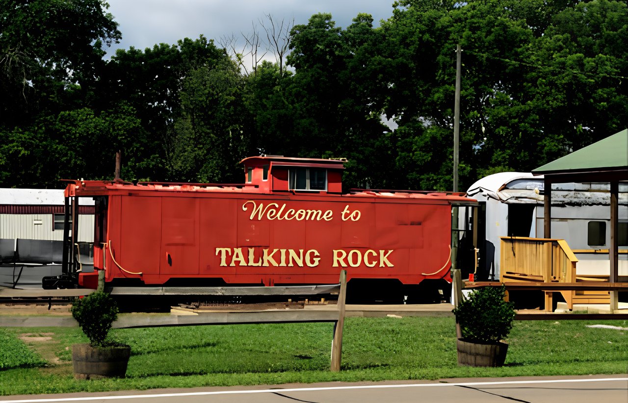 Red caboose welcoming visitors to Talking Rock beside a road.