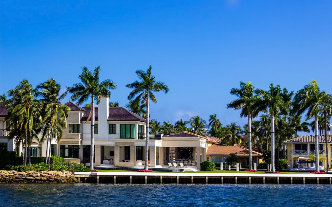 Waterfront homes with palm trees and docks along a tropical shoreline.