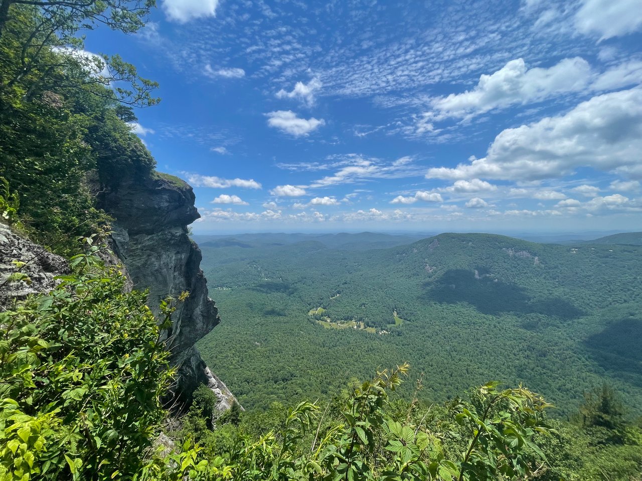 Rocky cliff overlooking a forested valley and distant mountains in Highlands NC