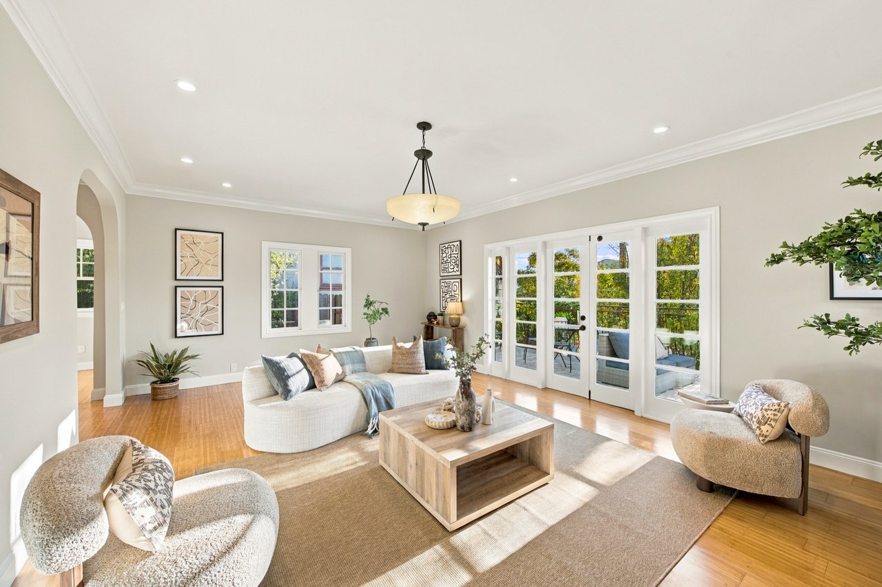 Staged living room with a curved white sofa, wood coffee table, and French doors opening to a patio.