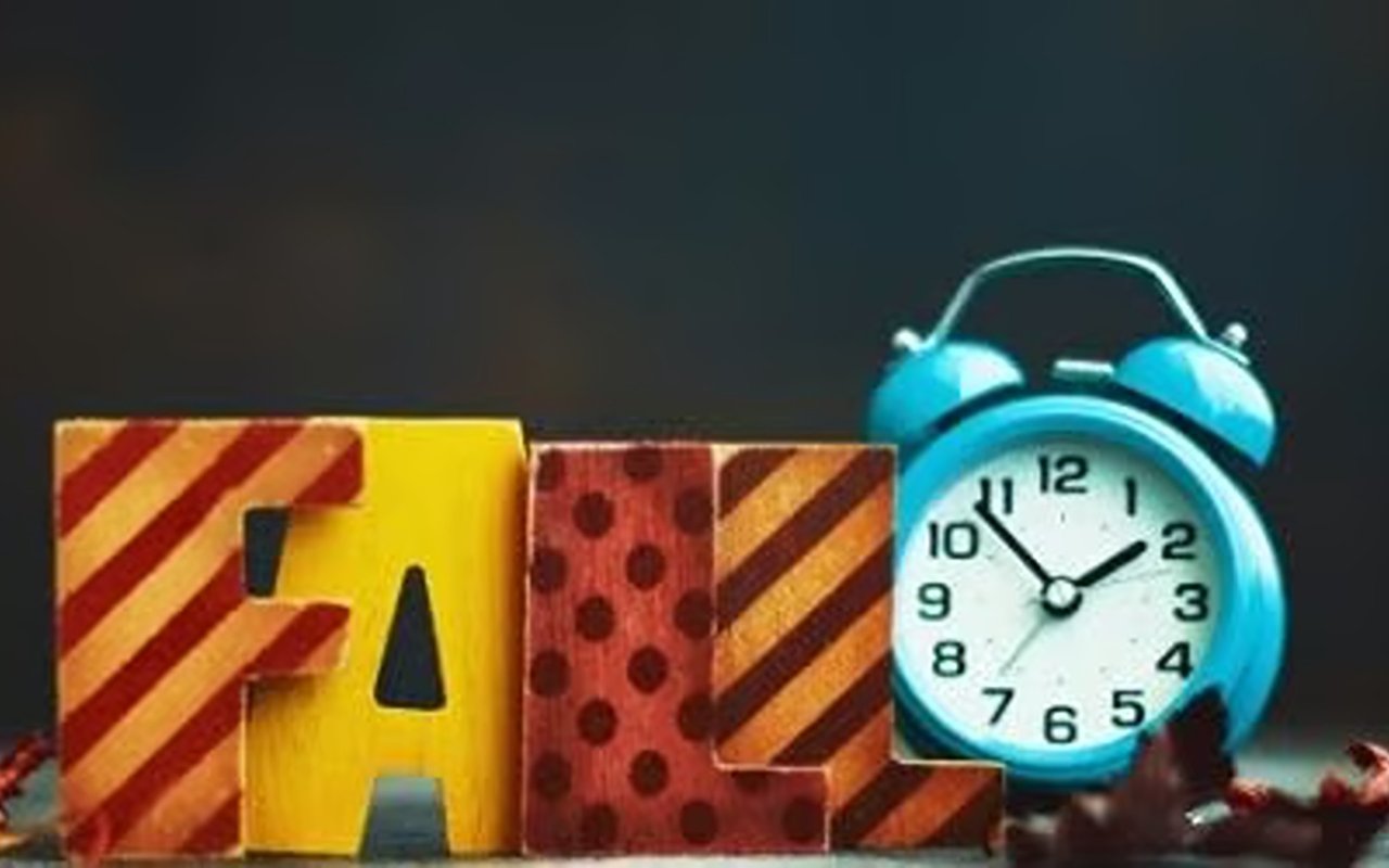 Decorative fall letters beside a turquoise alarm clock.