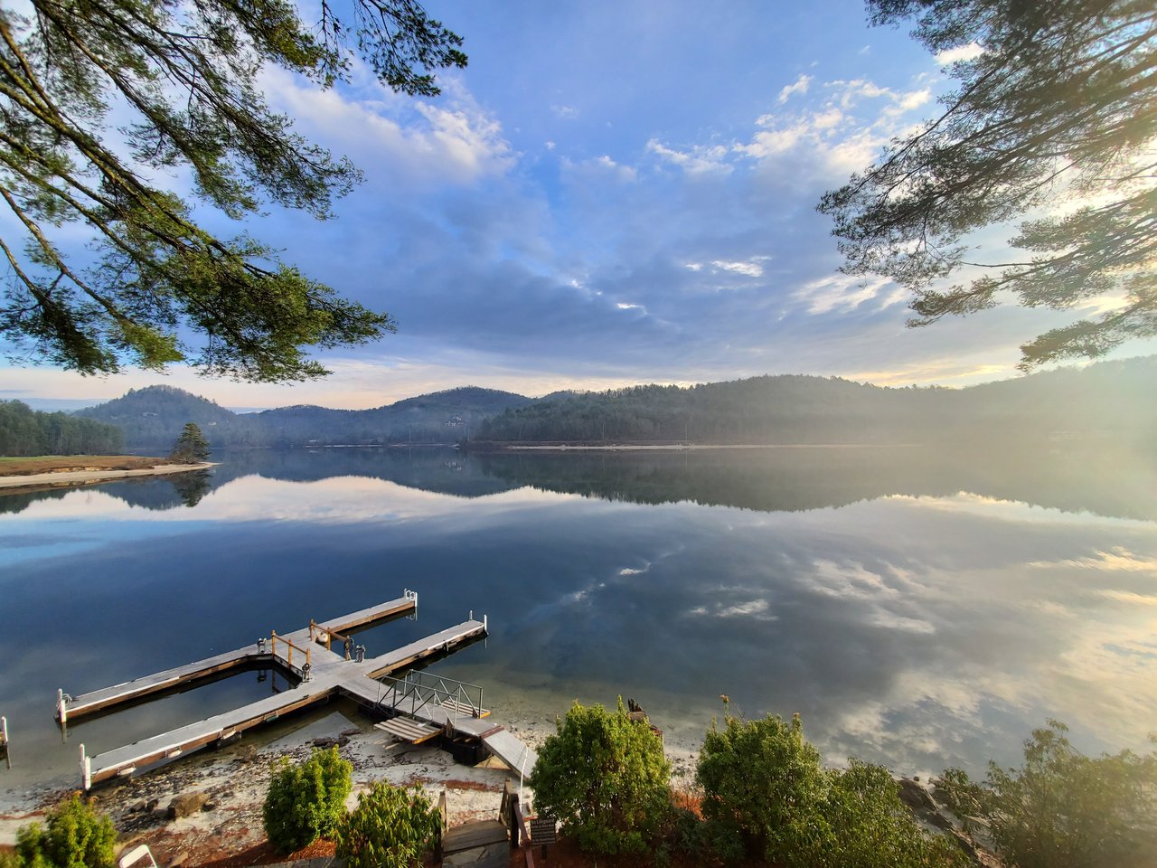Boat dock on calm Lake Glenville reflecting the surrounding mountains and sky near Cashiers, NC