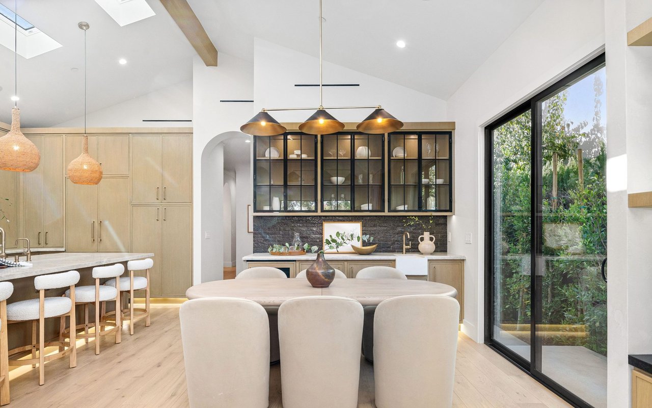 Open-plan kitchen and dining area with light wood cabinetry and black-framed garden doors.