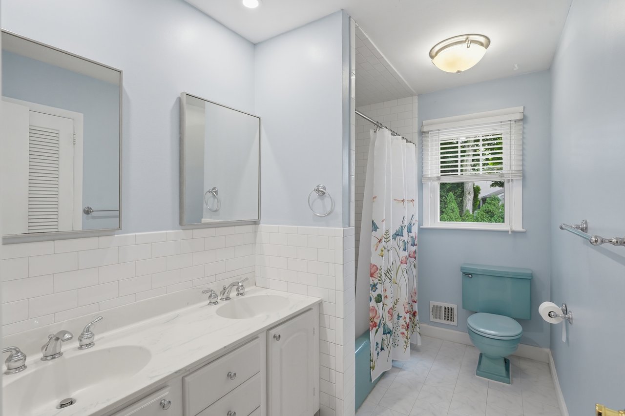 Featuring double sink vanity, tub, shower, toilet and laundry chute