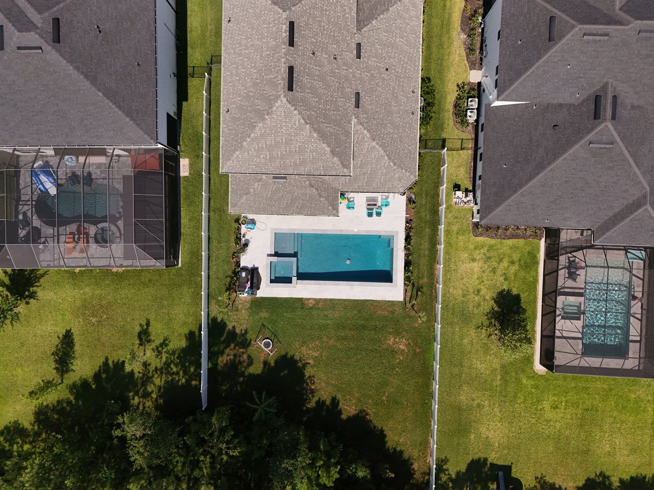 Aerial view of a backyard pool and patio between neighboring homes.