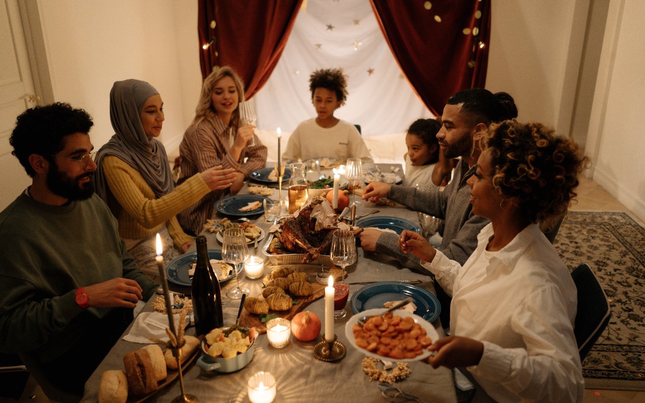 A family shares a candlelit Thanksgiving dinner with roast turkey and side dishes.