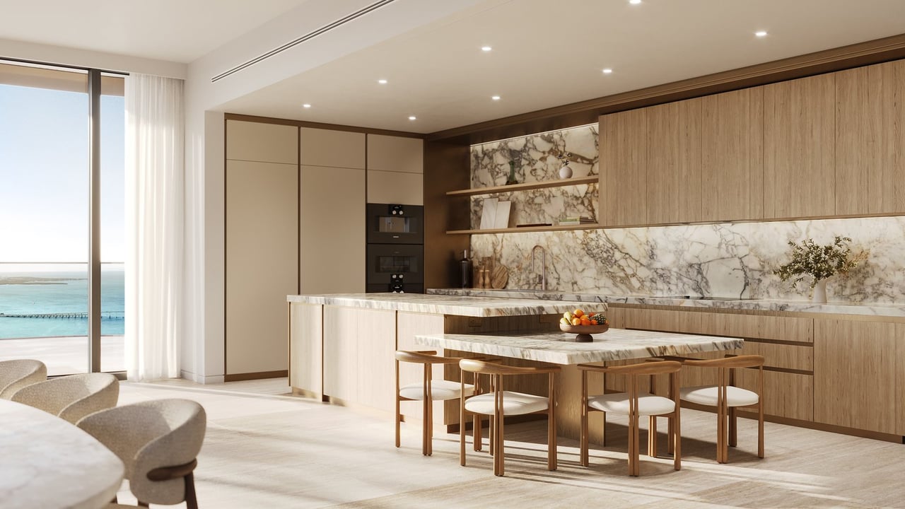 Modern kitchen with a marble island and dining table overlooking the water.