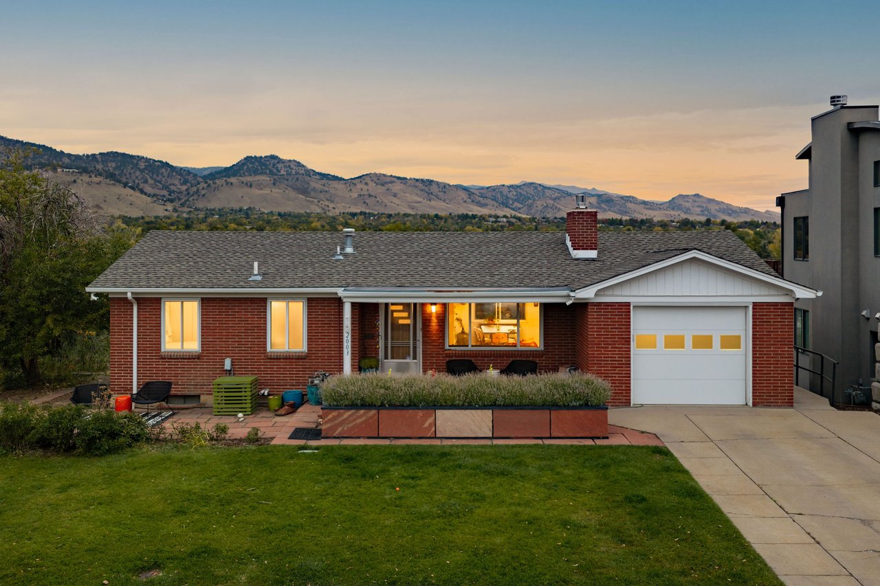 Twilight view of the brick home at 2003 Balsam Drive in Boulder with a wide front lawn and foothills on the horizon