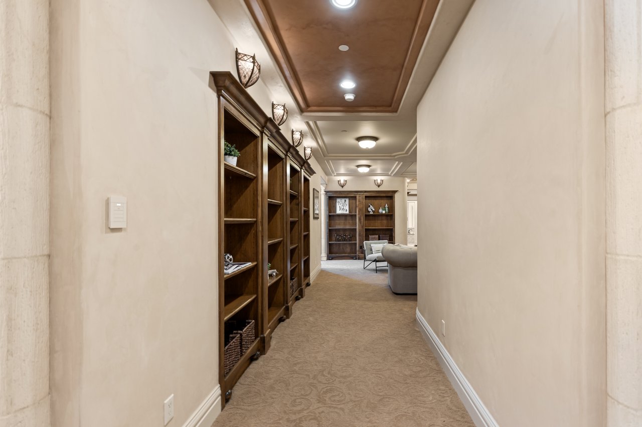 Carpeted hallway with dark built-in bookcases and a sitting area at the far end.