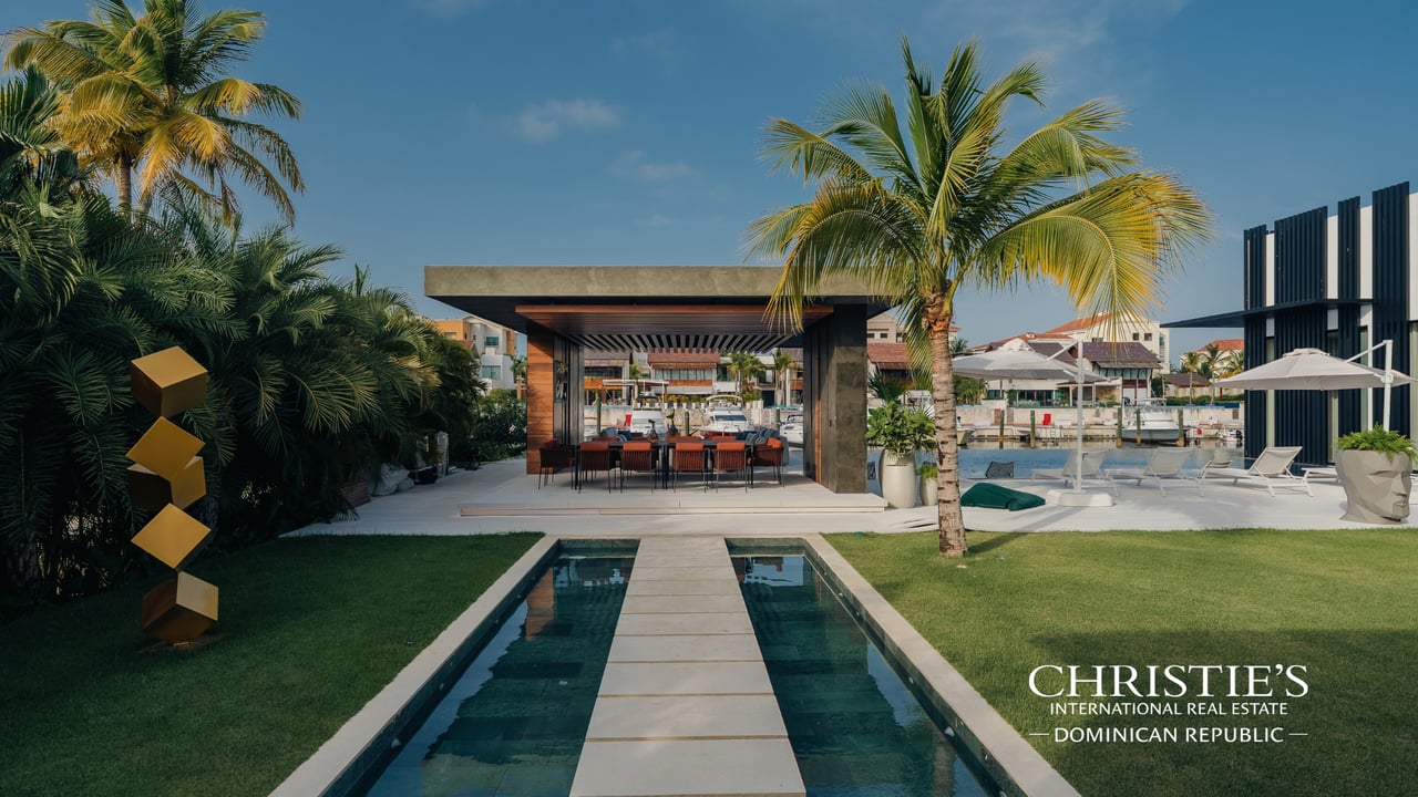 Modern Cap Cana villa with a narrow pool, covered dining pavilion, and marina beyond.