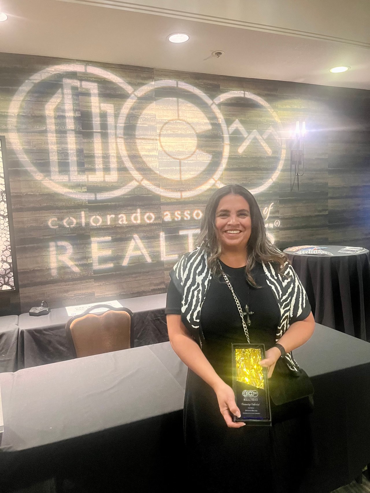 Giovanna Kennedy holds her award in front of a Colorado REALTORS backdrop.