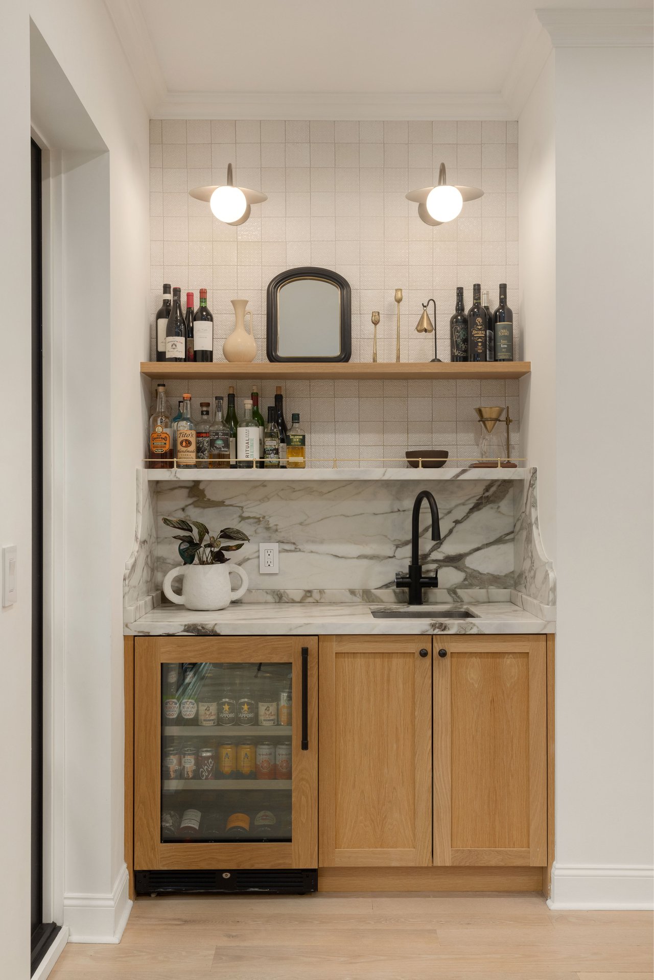 Built-in wet bar nook featuring natural oak cabinetry, a marble backsplash with open shelving, and a built-in beverage cooler.