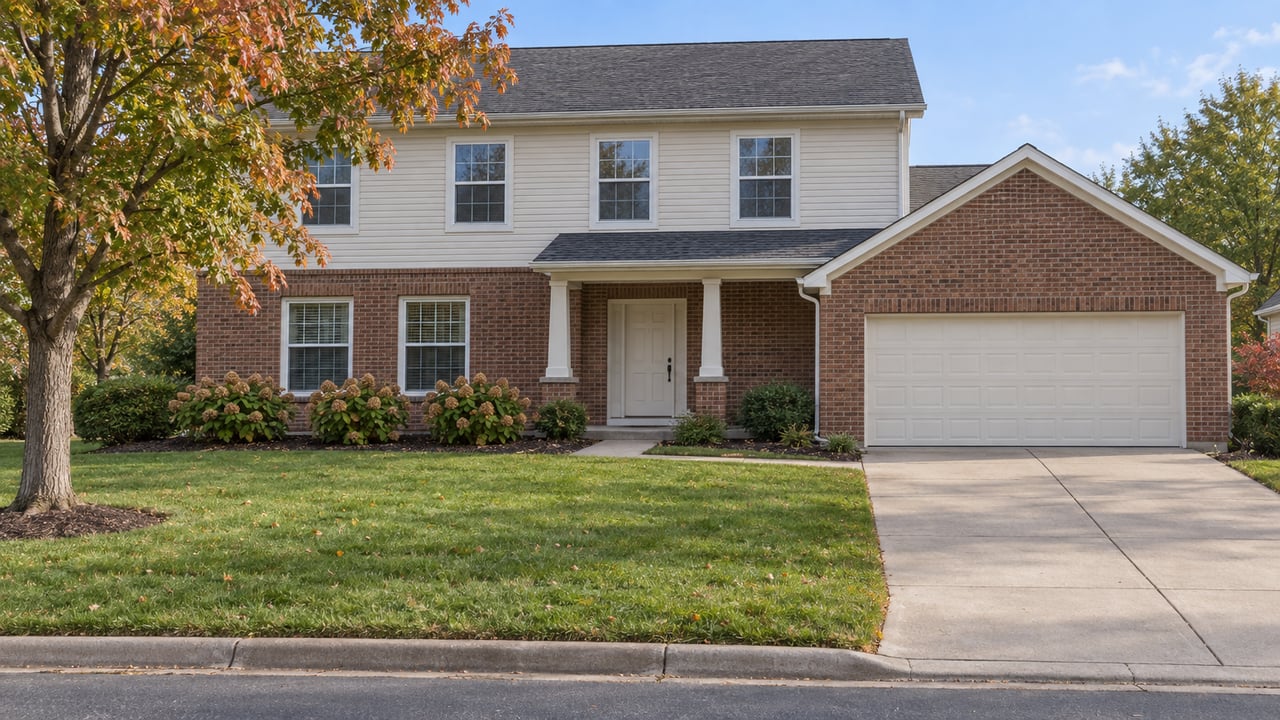 Two-story brick-and-siding house with an attached garage, covered entry, and autumn landscaping.