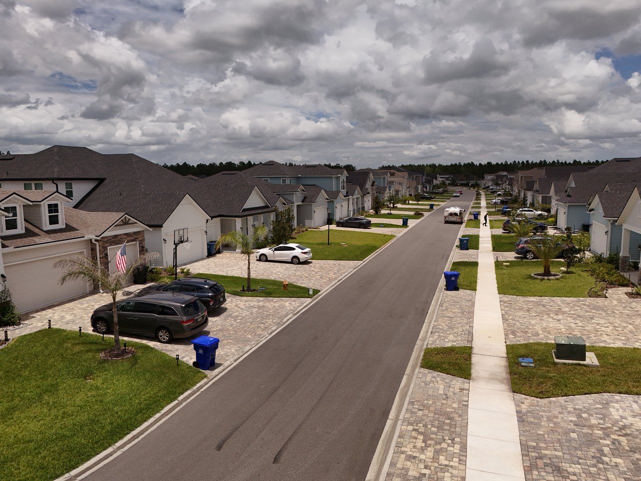 Residential street lined with modern homes, lawns, and paved driveways.