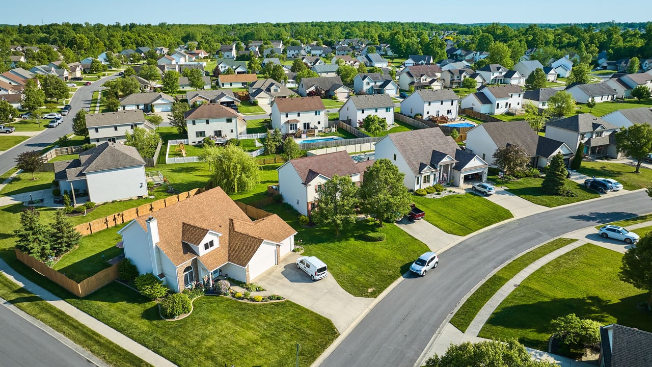 Aerial view of a leafy neighborhood with detached homes and curving residential streets.