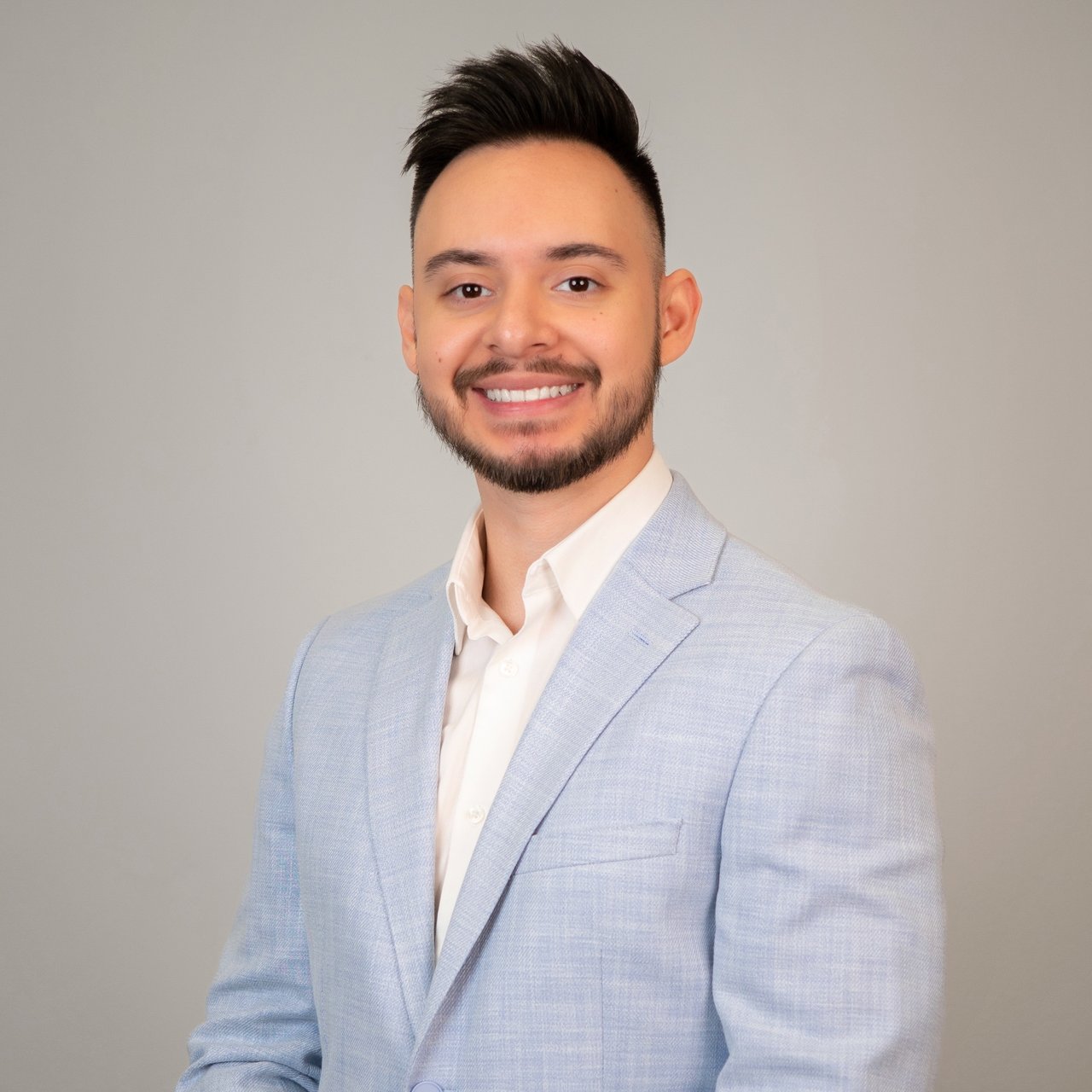 Kevin Mendez smiling in a light blue blazer and white shirt.