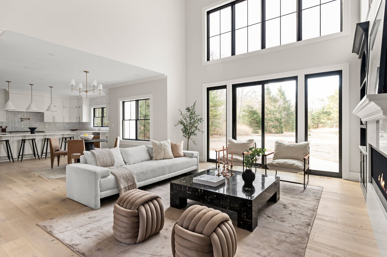 Open-plan living room with a white sofa, black marble coffee table, and tall black-framed windows.