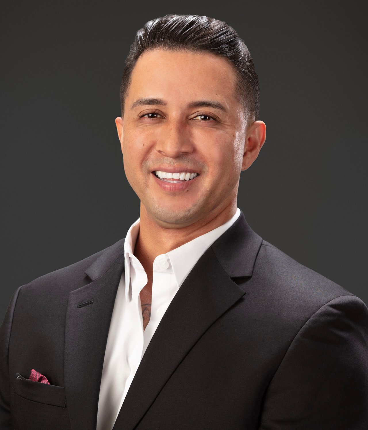 Gabe Mendez smiling in a dark suit jacket and white shirt.