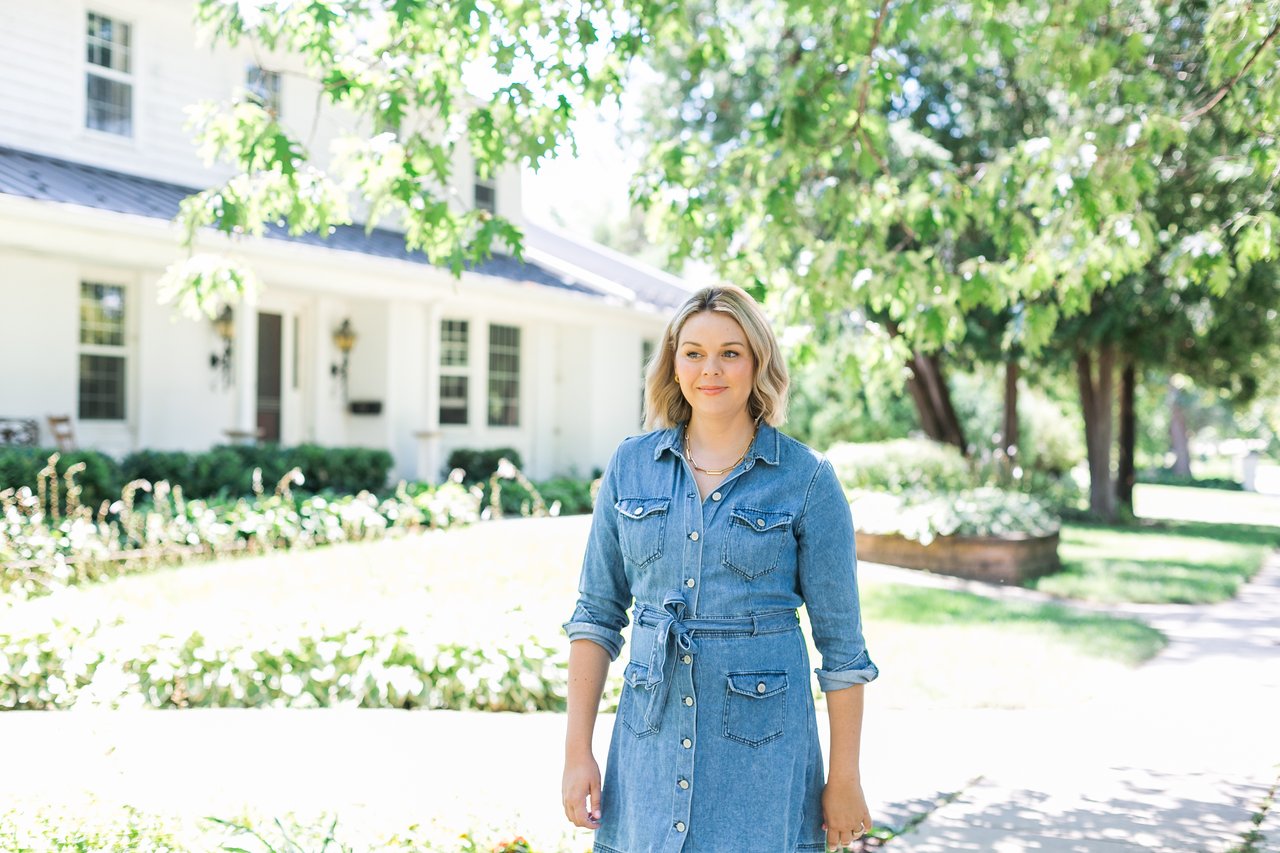 Cait Berry of Insiders Realty standing in a bright, tree-lined Madison, Wisconsin neighborhood, highlighting the best areas for young professionals to live, work, and play.