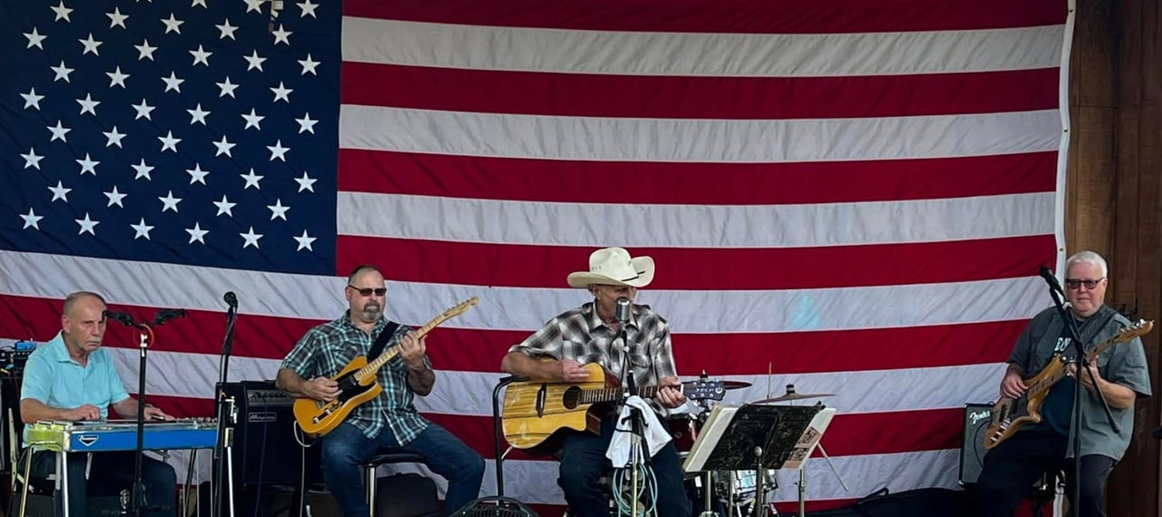 The Alton Lane Band on stage with an american flag in the background. The band will be playing at Vignette Realty's sponsored Sweet Carolina Music Festival