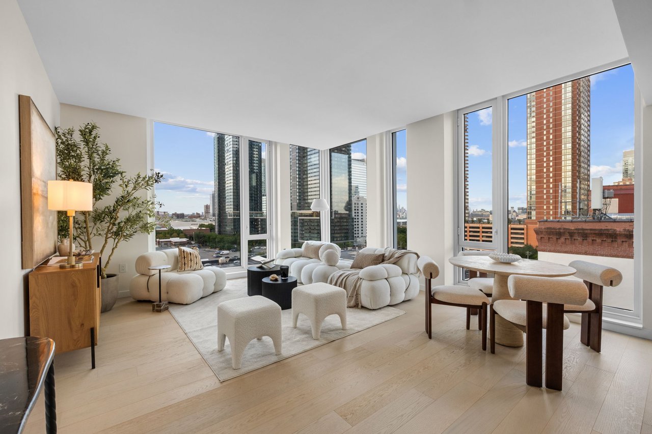 Furnished condo living and dining area with a white sectional and expansive city views through corner windows.