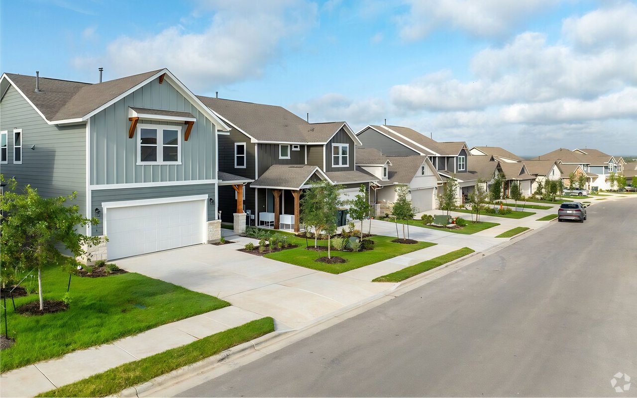 Modern homes line a residential street with landscaped lawns and sidewalks.