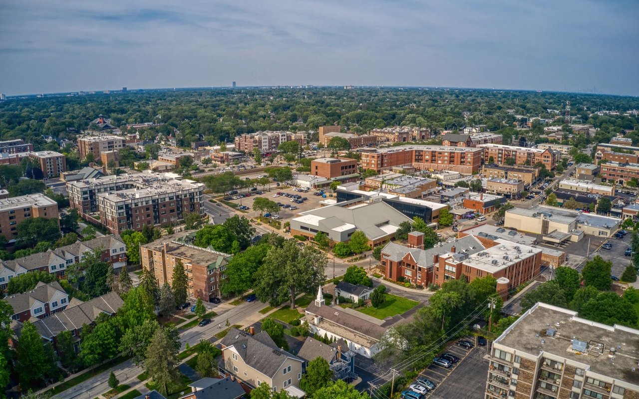 Aerial view of a suburban downtown with mid-rise buildings and tree-lined residential streets.