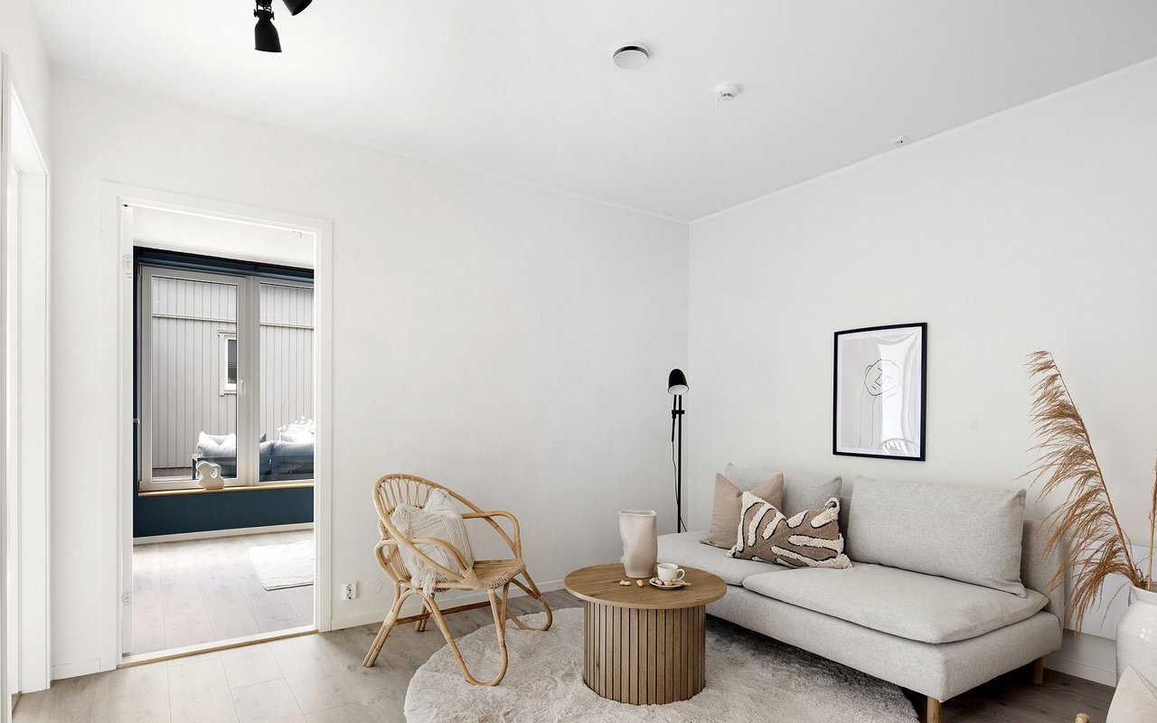 Bright living room with a gray sofa, round wood coffee table, and woven rattan chair.