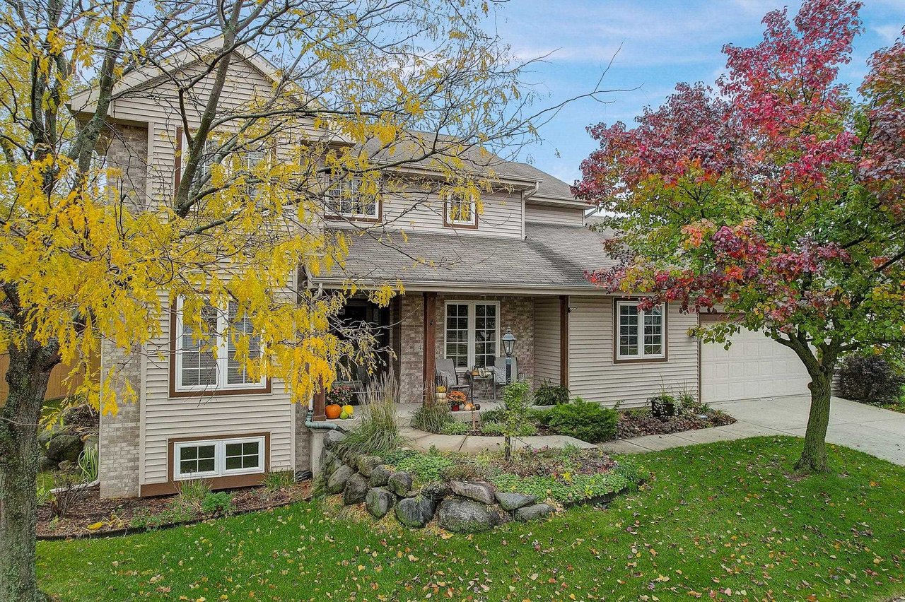 A well-maintained two-story home in the Madison, Wisconsin area with a covered front porch and autumn trees in the front yard.