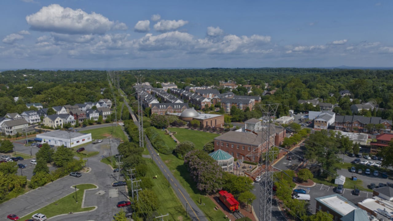 Aerial view of a leafy suburban neighborhood with brick buildings and a road through the center.