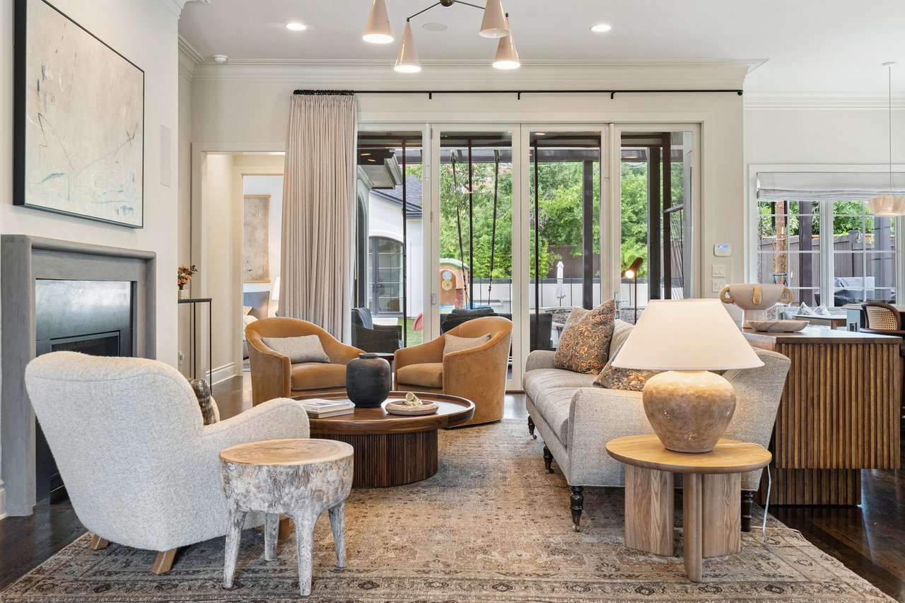 Great room with a stone fireplace and sliding glass doors opening to the backyard, furnished by Ashby Collective, at 2600 Westover Road in Tarrytown, Austin.