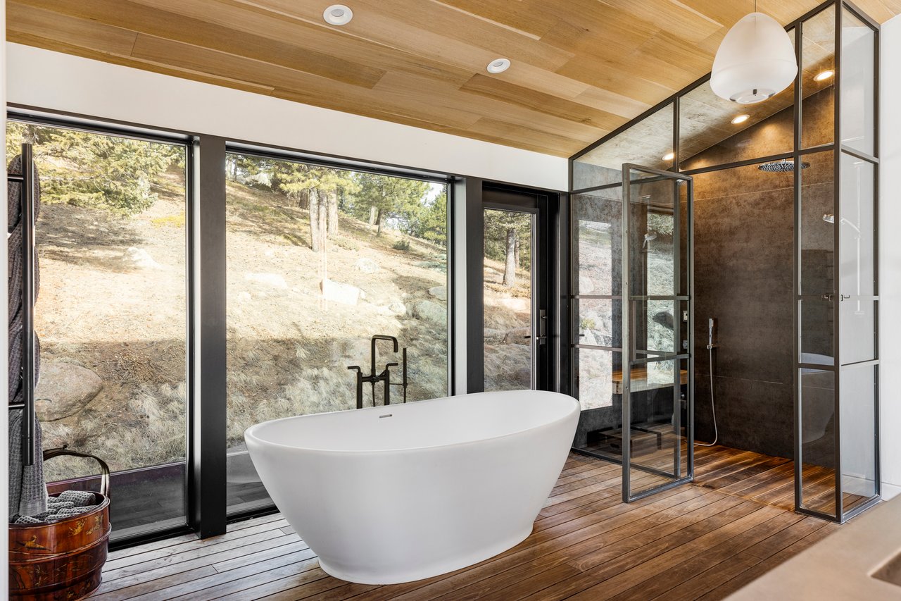 Luxury Boulder bathroom with freestanding tub, mountain views through full-height windows, and glass shower enclosure