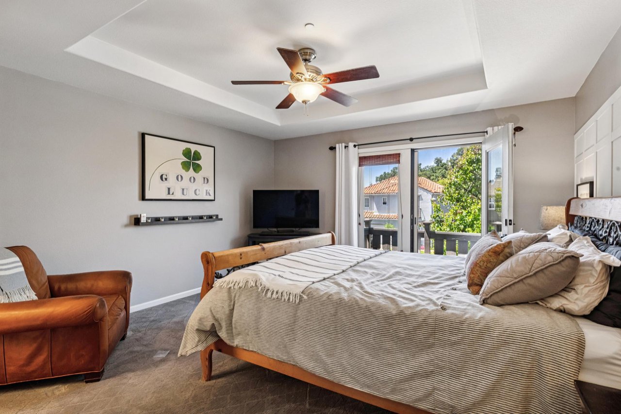 Spacious primary suite featuring a Juliet balcony, natural light, and peaceful treetop views.