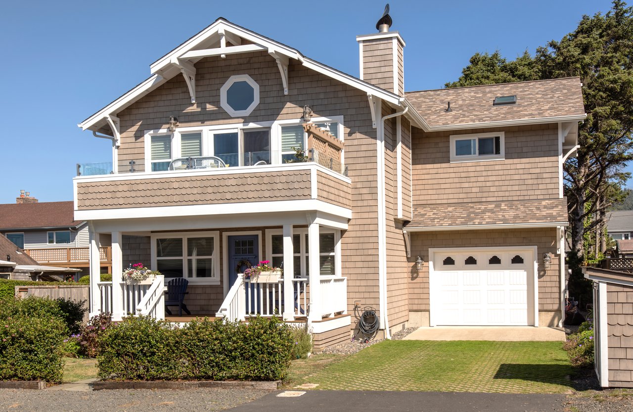 Two-story shingle-sided home with a covered porch, upper balcony, and attached garage.