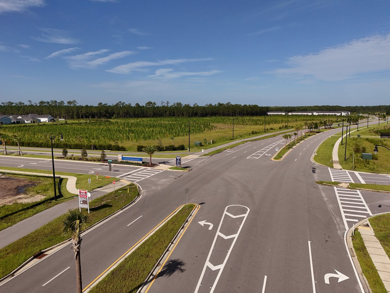 Silver Meadows entrance road with its community sign, landscaped medians, and homes in the distance.