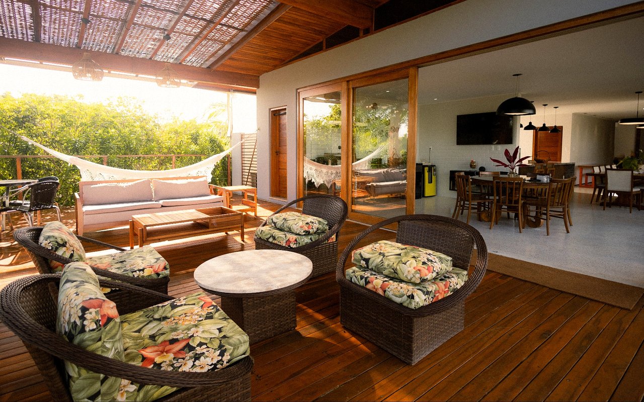 Covered patio with wood decking, wicker lounge seating, a hammock, and an open connection to the dining area.