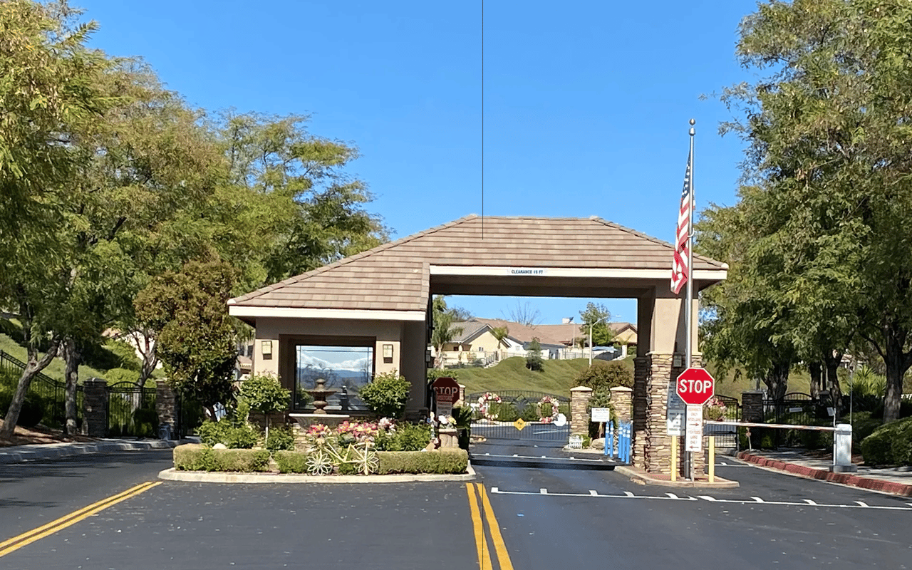 Private guard-gated entry gatehouse and landscaped entrance to a residential community in Menifee, CA.